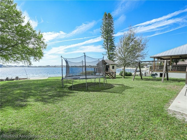 view of yard with a trampoline and a water view