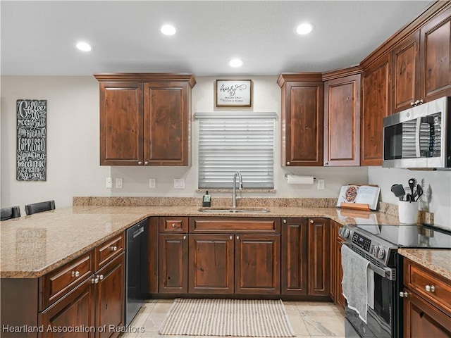 kitchen featuring stainless steel appliances, recessed lighting, a sink, light stone countertops, and a peninsula