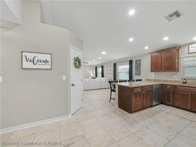 kitchen featuring stainless steel dishwasher, kitchen peninsula, a healthy amount of sunlight, and a breakfast bar