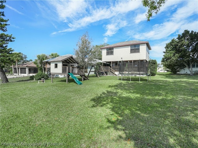 rear view of property with a playground and a yard