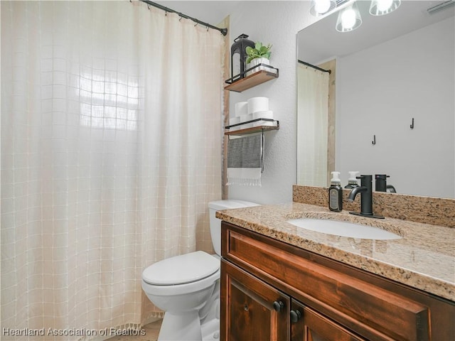 bathroom with toilet, vanity, and visible vents