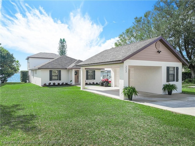 ranch-style house with a shingled roof, a front yard, driveway, and stucco siding