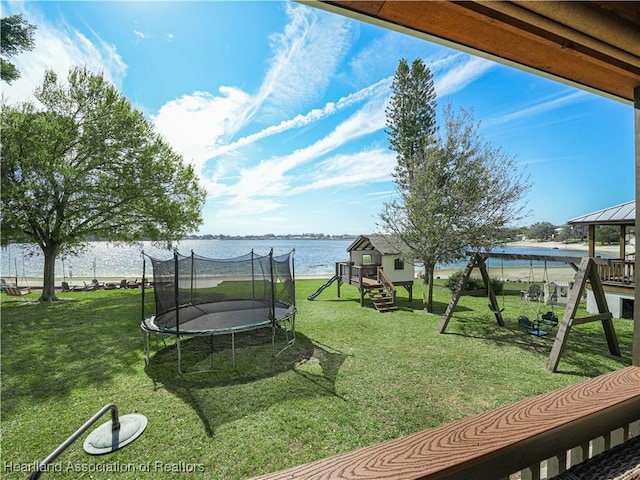 view of yard with a playground, a water view, and a trampoline