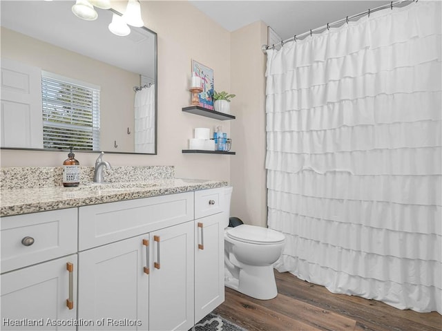 bathroom with toilet, curtained shower, wood finished floors, and vanity