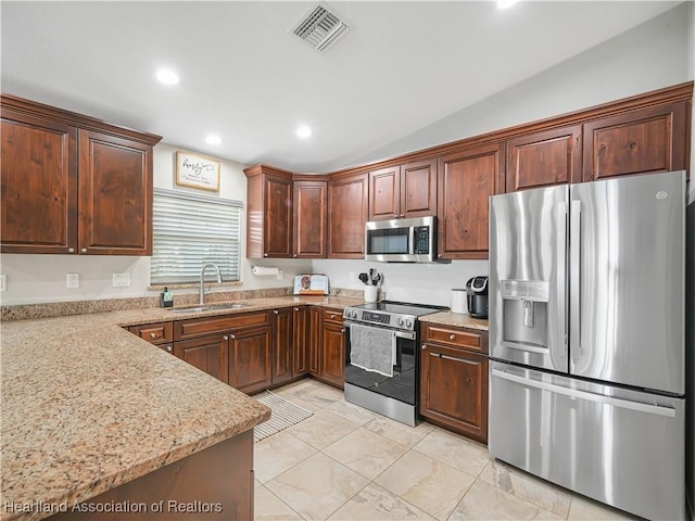 kitchen featuring visible vents, lofted ceiling, appliances with stainless steel finishes, light stone countertops, and a sink