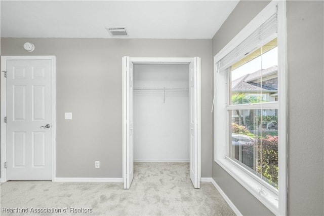 unfurnished bedroom with light colored carpet and a closet