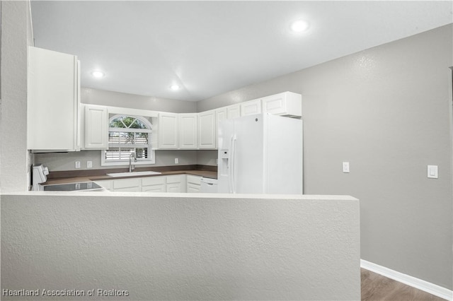 kitchen featuring sink, dark hardwood / wood-style floors, kitchen peninsula, white appliances, and white cabinets