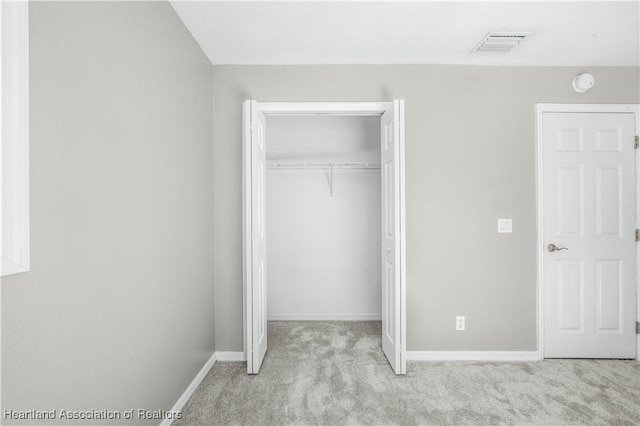 unfurnished bedroom featuring light carpet and a closet