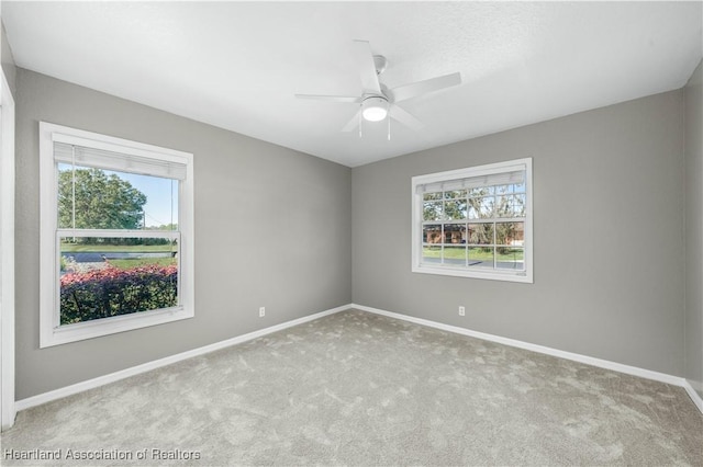 carpeted spare room featuring ceiling fan and a wealth of natural light