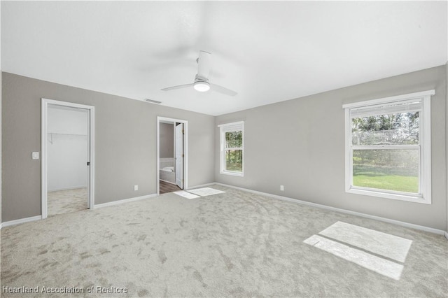 unfurnished bedroom with connected bathroom, a spacious closet, ceiling fan, a closet, and carpet