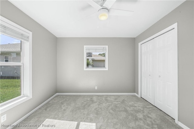 unfurnished bedroom featuring ceiling fan, light carpet, and a closet