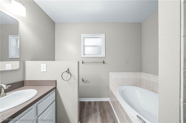 bathroom featuring vanity, a relaxing tiled tub, and wood-type flooring