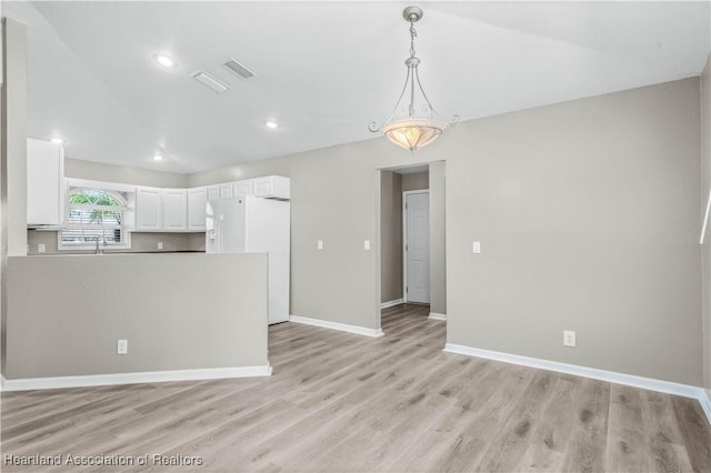 kitchen featuring sink, hanging light fixtures, white refrigerator with ice dispenser, light hardwood / wood-style floors, and white cabinets