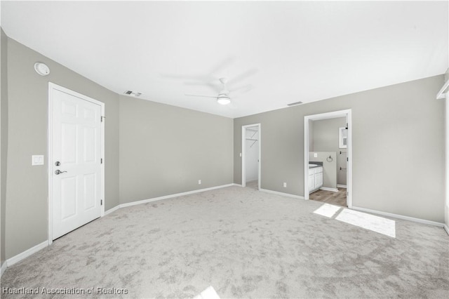 unfurnished bedroom with connected bathroom, ceiling fan, a closet, and light colored carpet