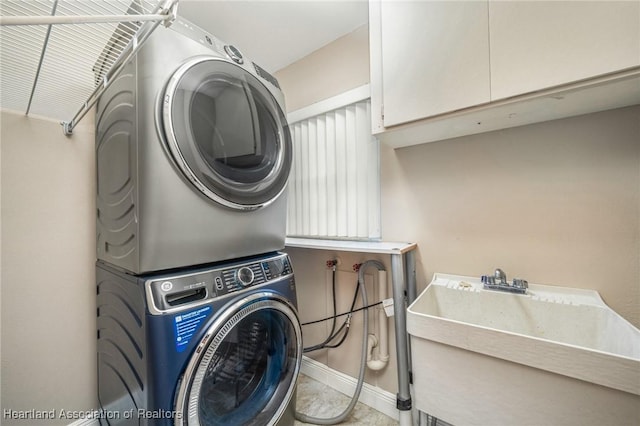 laundry area with sink, cabinets, and stacked washer and clothes dryer