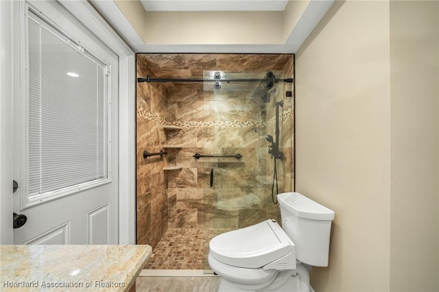 bathroom with tile patterned floors, toilet, and tiled shower