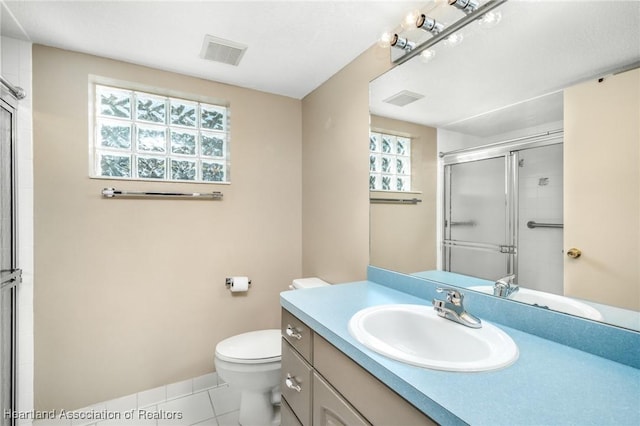 bathroom featuring tile patterned flooring, vanity, an enclosed shower, and toilet