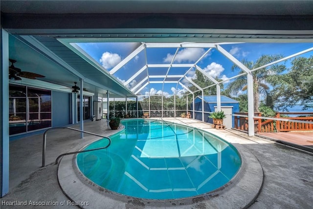 view of pool with ceiling fan, a patio area, a lanai, and a storage shed