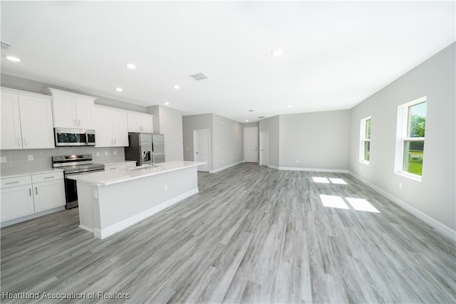 4737 Myrtle Dr, Sebring, FL 33872 - kitchen featuring appliances with stainless steel finishes, an island with sink, tasteful backsplash, light countertops, and light wood-style flooring