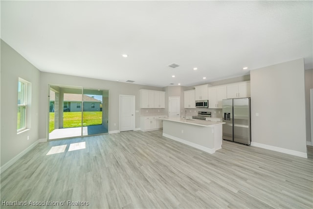 4737 Myrtle Dr, Sebring, FL 33872 - kitchen featuring appliances with stainless steel finishes, light countertops, light wood-style floors, white cabinets, and an island with sink