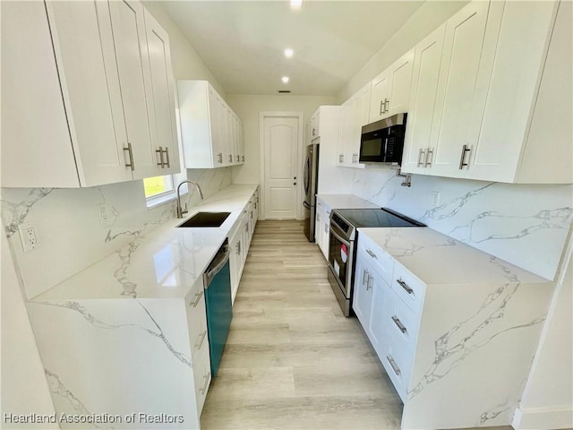 kitchen featuring stainless steel appliances, backsplash, white cabinets, light stone counters, and sink