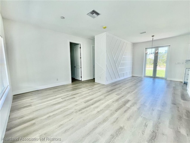 empty room featuring an inviting chandelier and light hardwood / wood-style flooring