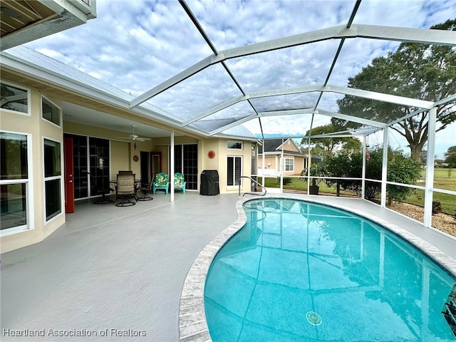 view of swimming pool featuring a lanai, ceiling fan, and a patio