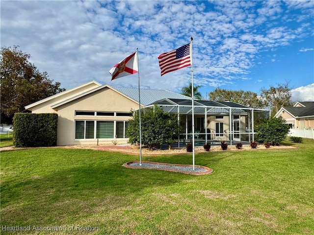 back of property featuring glass enclosure and a yard