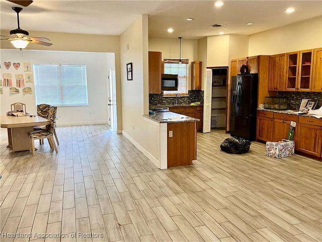 kitchen featuring black appliances, ceiling fan, dark stone counters, and tasteful backsplash