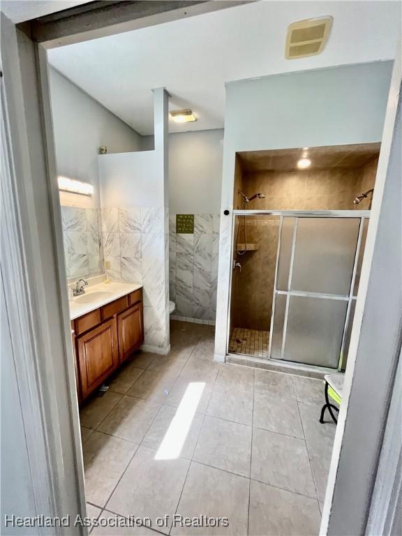 bathroom featuring tile patterned flooring, vanity, toilet, and a shower with shower door