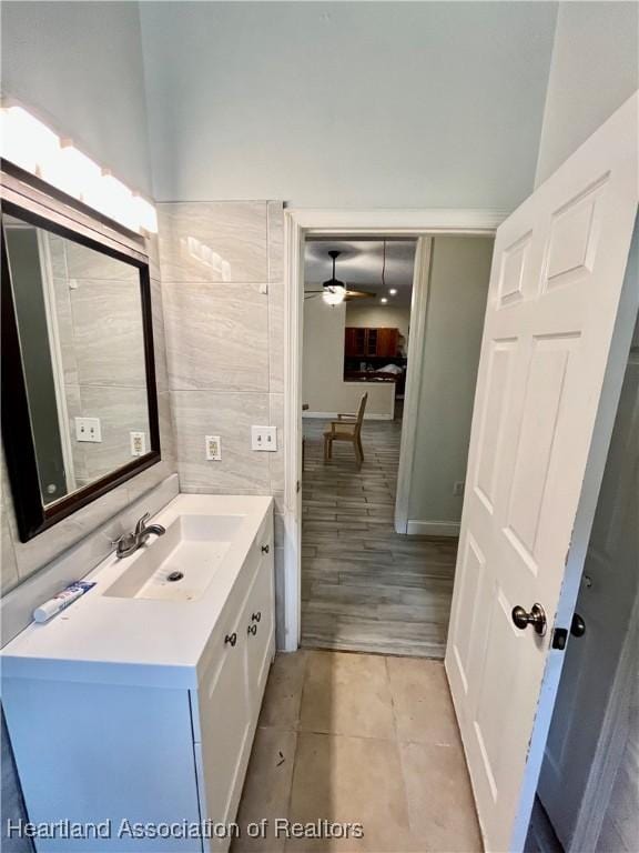 bathroom with tile patterned floors, ceiling fan, tile walls, and vanity