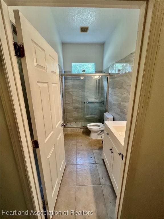 bathroom with tile patterned floors, an enclosed shower, vanity, a textured ceiling, and toilet