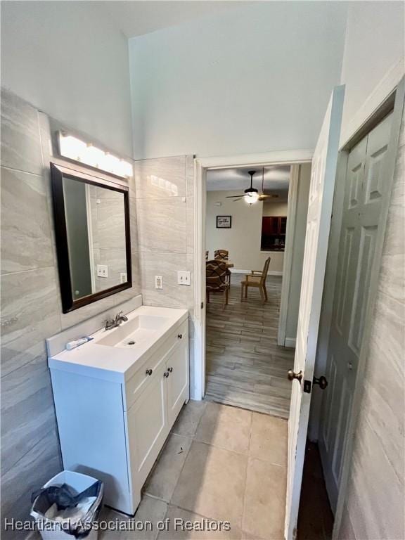 bathroom with tile patterned flooring, ceiling fan, tile walls, and vanity