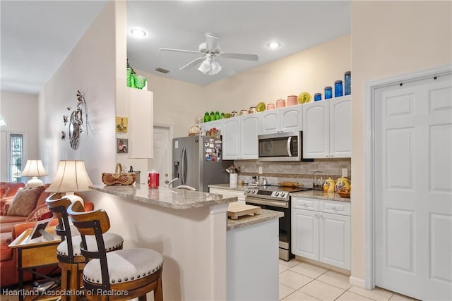 2033 Ashley Oaks Cir, Sebring, FL 33870 - kitchen featuring light tile patterned floors, ceiling fan, white cabinetry, a kitchen breakfast bar, and appliances with stainless steel finishes