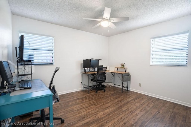 office featuring a textured ceiling, ceiling fan, a healthy amount of sunlight, and dark wood-type flooring