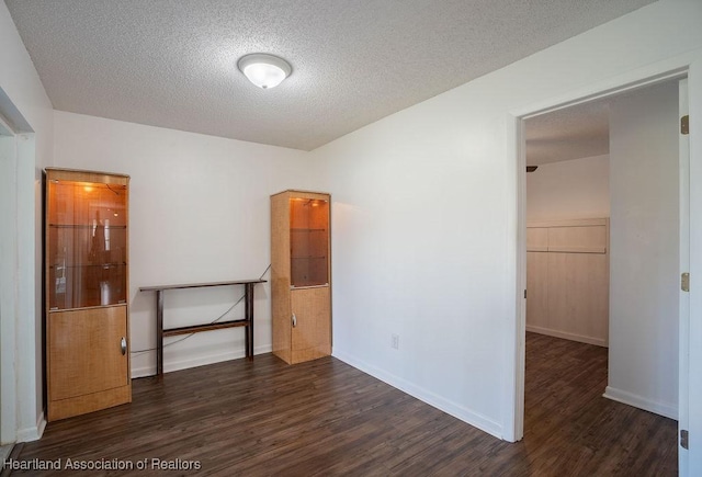 spare room featuring a textured ceiling and dark hardwood / wood-style floors