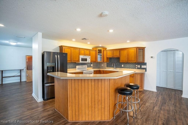 kitchen featuring electric range, sink, dark hardwood / wood-style flooring, stainless steel refrigerator with ice dispenser, and a kitchen island