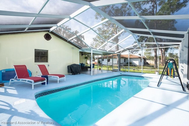 view of pool with glass enclosure, a patio, and grilling area