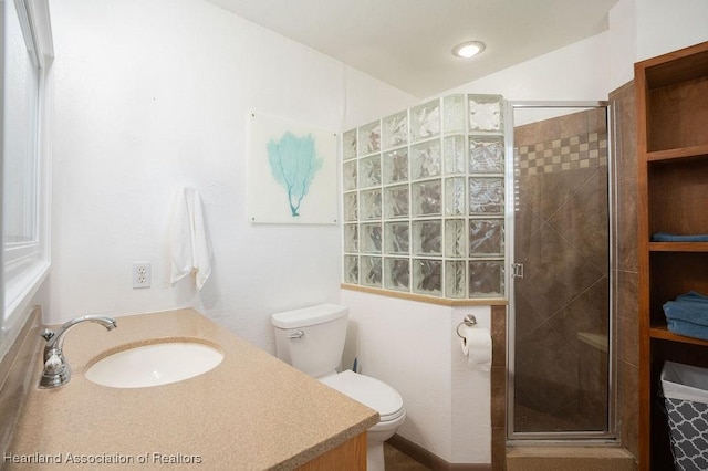 bathroom featuring vanity, a shower with shower door, and toilet