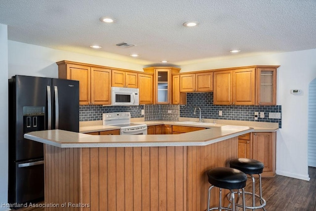 kitchen with dark wood-type flooring, electric stove, sink, a textured ceiling, and refrigerator with ice dispenser