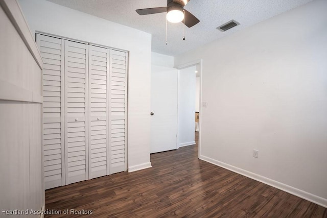 unfurnished bedroom featuring dark hardwood / wood-style flooring, ceiling fan, a closet, and a textured ceiling