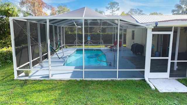 back of house featuring a lawn, glass enclosure, and a patio area