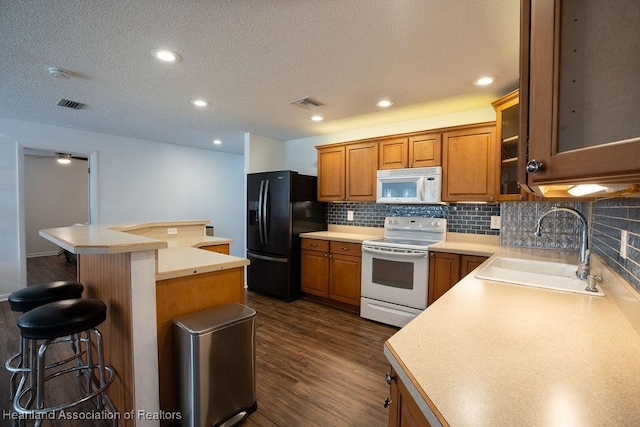 kitchen featuring sink, a center island, dark hardwood / wood-style floors, white appliances, and a breakfast bar