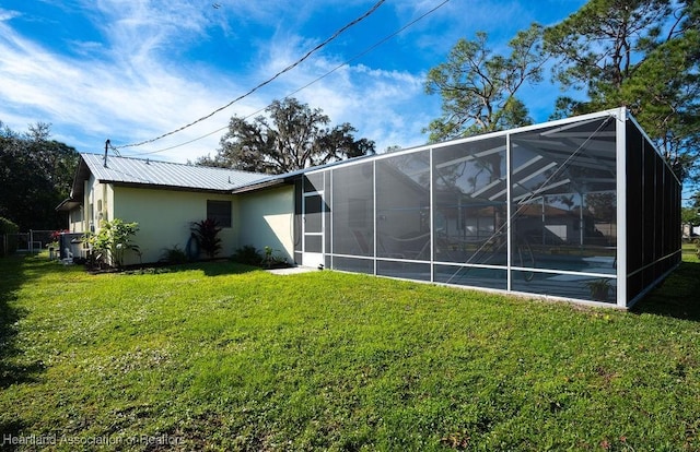 rear view of property featuring glass enclosure and a yard