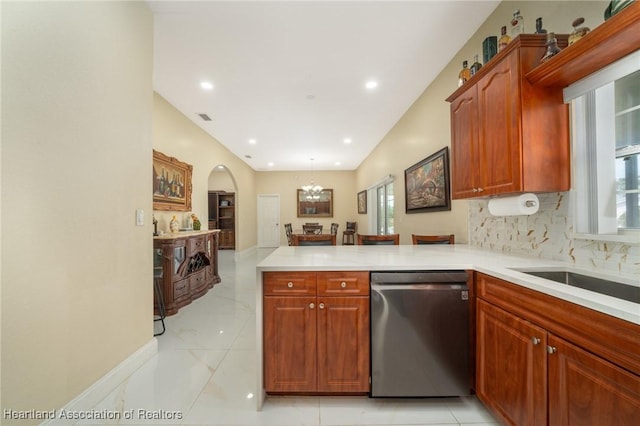 kitchen featuring pendant lighting, dishwasher, an inviting chandelier, decorative backsplash, and kitchen peninsula