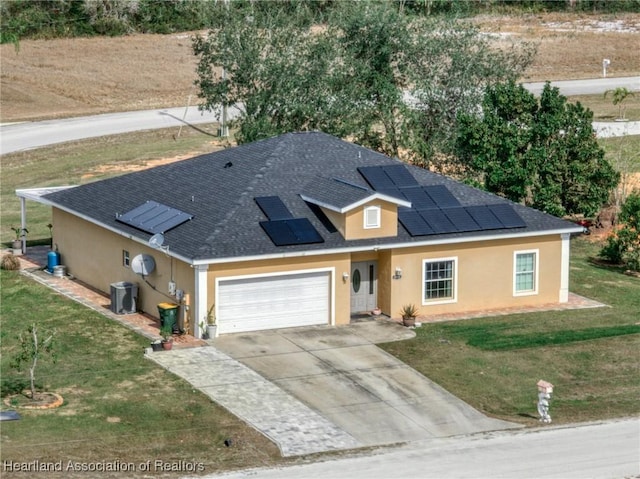 view of front of house with a garage, cooling unit, a front yard, and solar panels