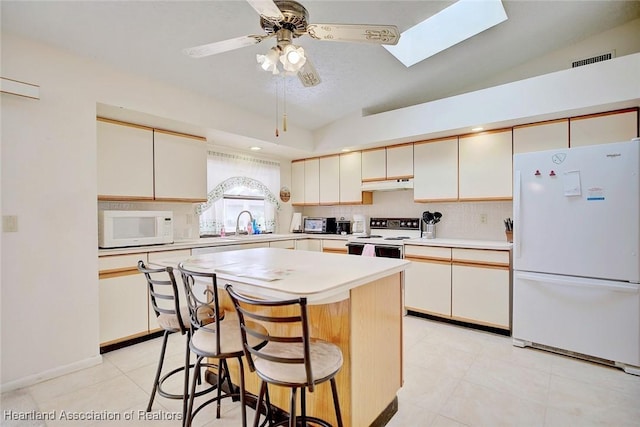 kitchen with a center island, white appliances, backsplash, lofted ceiling with skylight, and a kitchen bar