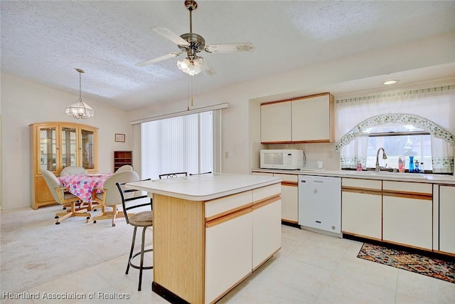 kitchen featuring a textured ceiling, a kitchen island, pendant lighting, and white appliances