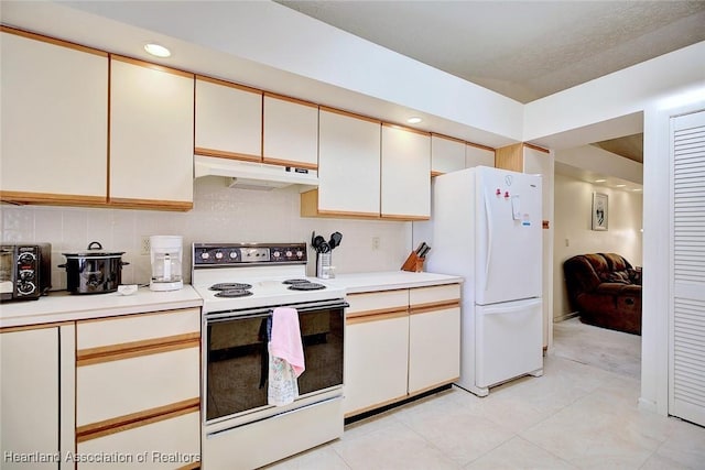 kitchen with white cabinets, light tile patterned flooring, white appliances, and backsplash