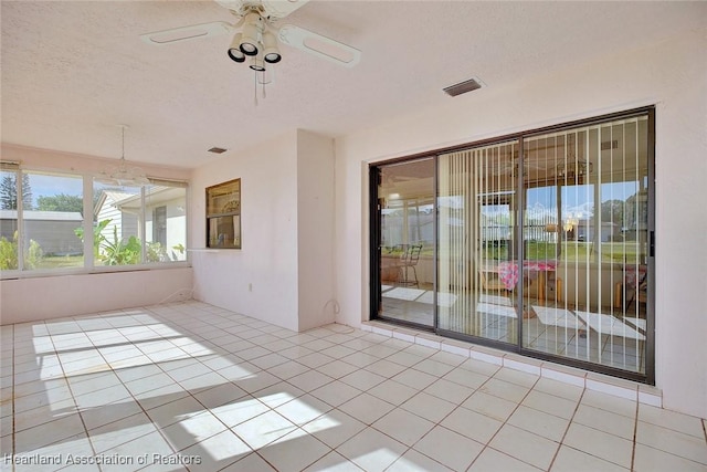 empty room with ceiling fan, light tile patterned floors, and a textured ceiling